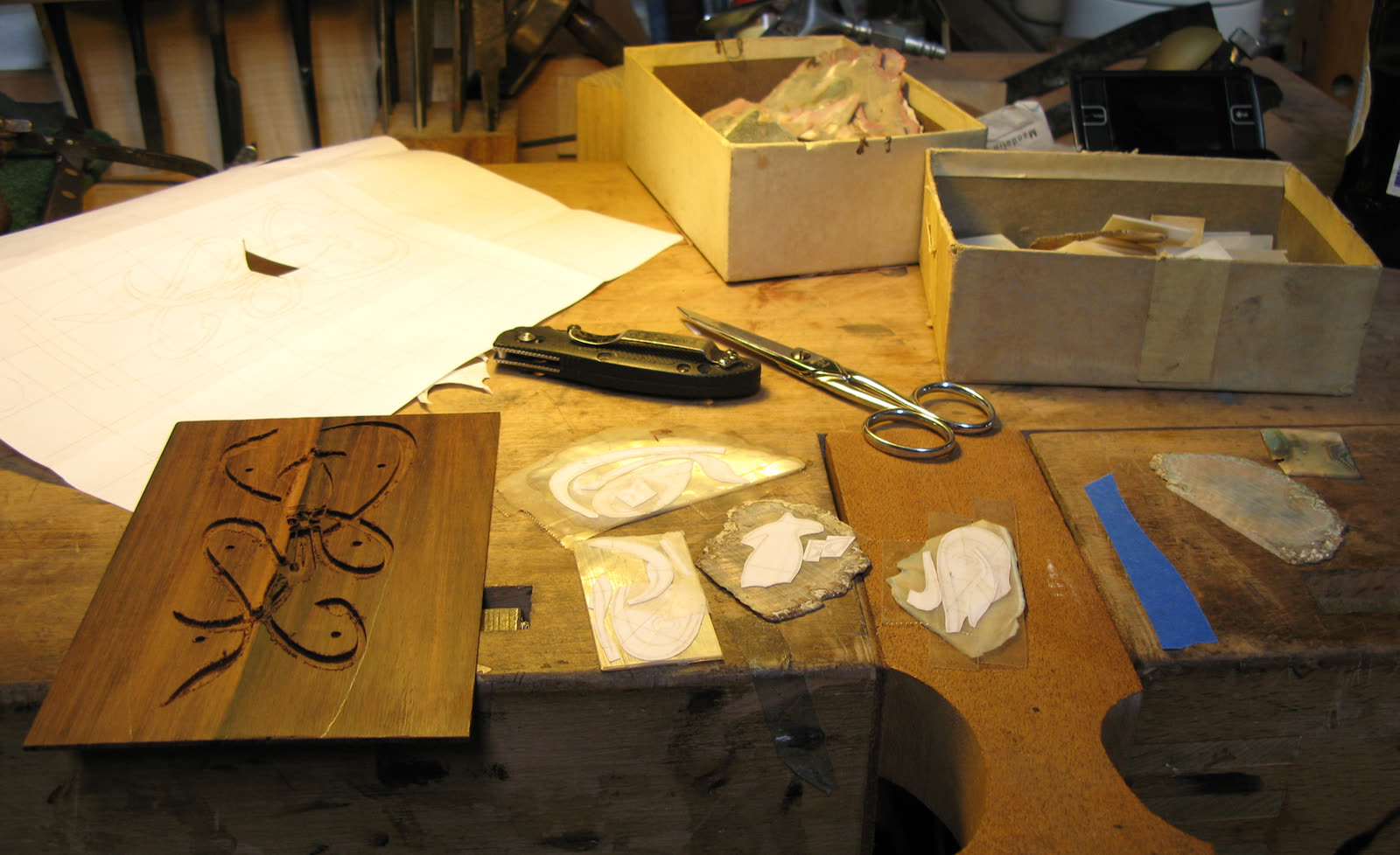 Shell blanks — paper templates taped on, mother-of-pearl and abalone shell, routed cavity visible behind
